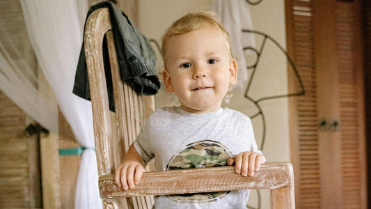 Petit garçon de 1 an assis sur une chaise en bois