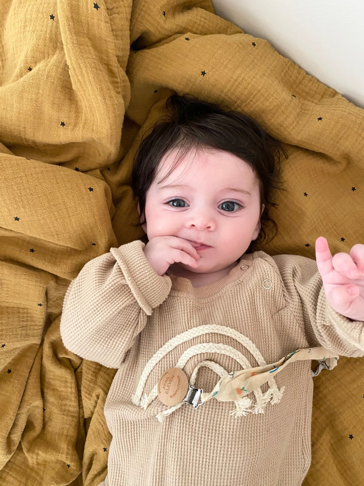 bébé allongé sur le dos qui suce ses doigts