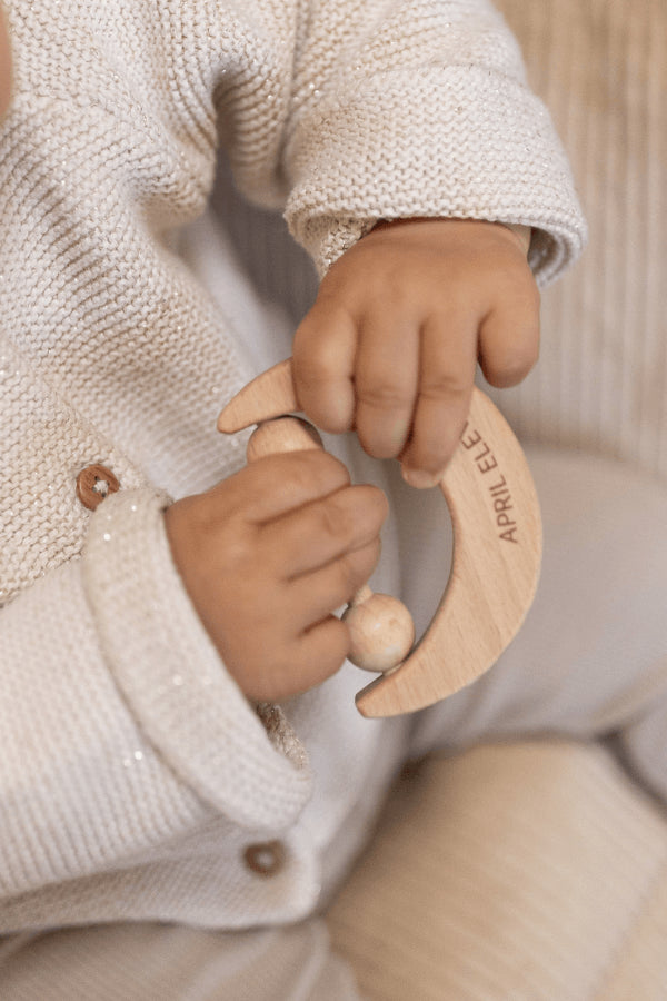 Bébé tenant un hochet en bois en forme de lune dans les mains