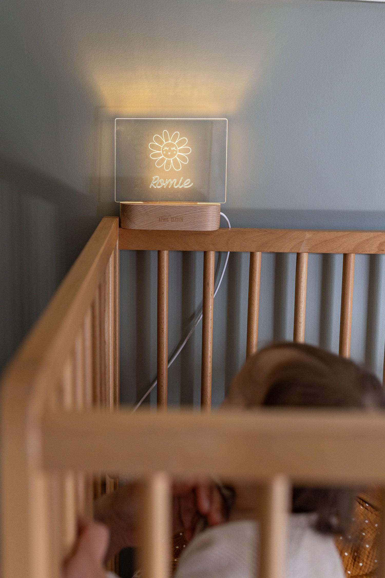 Veilleuse bébé personnalisée avec prénom posée près du lit, lumière douce pour le sommeil dans une chambre d’enfant